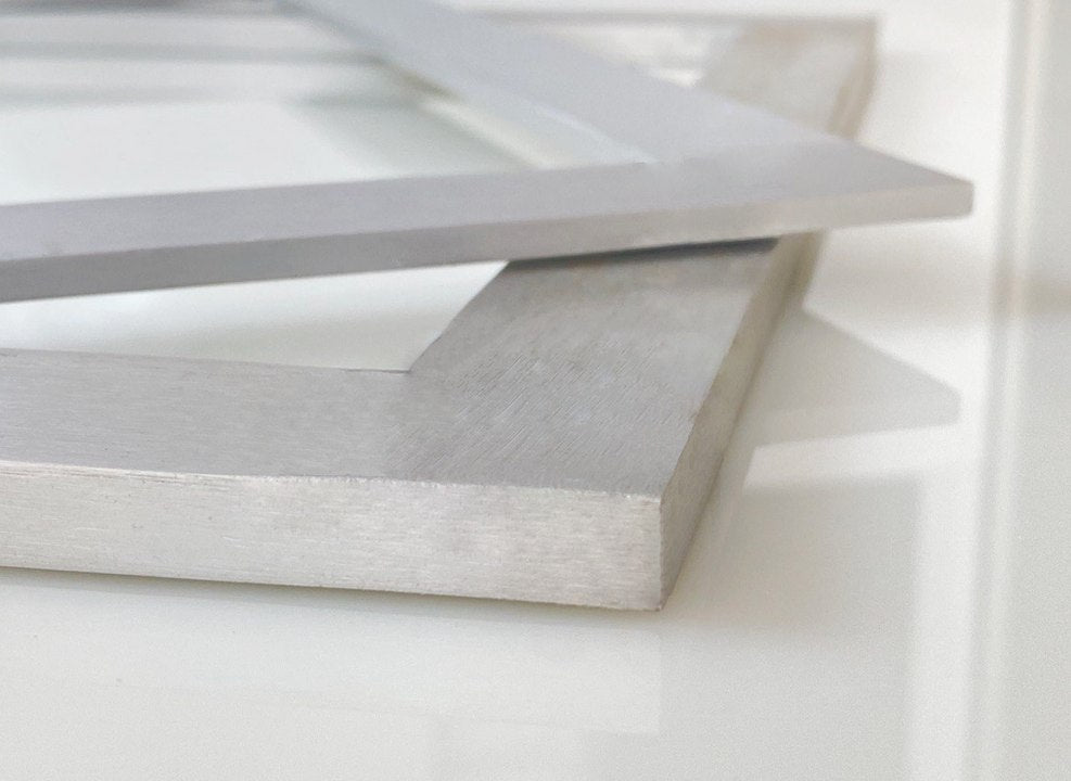 Two silver-colored aluminum ganache frames stacked on top of each other, with visible thickness and inner and outer dimensions, from Mangharam.