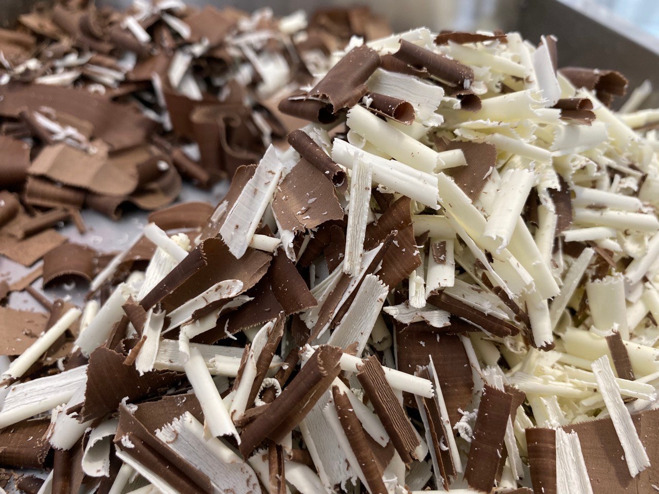 Beautiful image of curled and straight flakes in white and milk chocolate from Mangharam